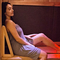 profile of women in towel sitting inside infrared sauna