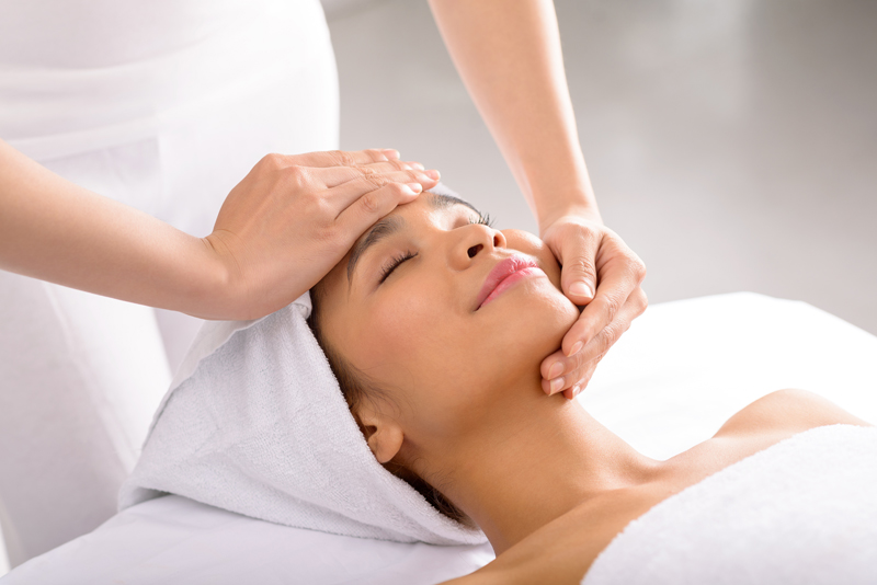 woman massaging face of client