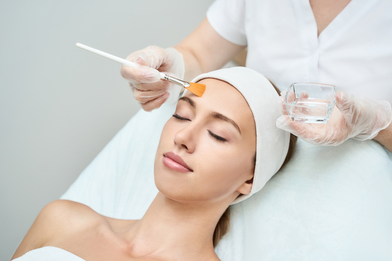 image of women applying a facial peel using brush to woman's face